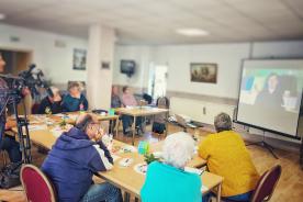 Senioren sitzen am Tisch und h&ouml;ren dem Vortrag des Digitalen Engels zu