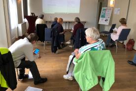 Senioren sitzen im Raum und unterhalten sich bei Digitalem Engel