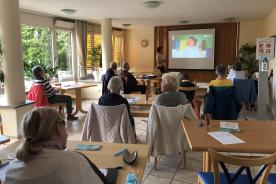 In M&ouml;lln sitzen Senioren im Raum und schauen auf Leinwand