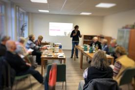 Senioren sitzen im Raum und h&ouml;ren einer Rede zu