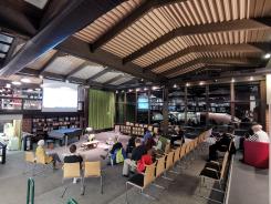 Die Teilnehmenden sitzen im Raum und schauen zur Pr&auml;sentation auf der Leinwand