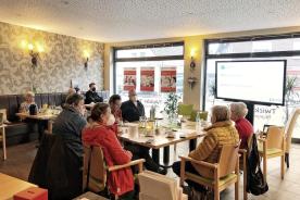 Senioren sitzen an Tischen un dh&ouml;ren einem Vortrag zu