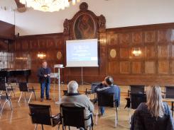 Die Teilnehmenden sitzen im Raum und schauen zur Pr&auml;sentation an der Leinwand
