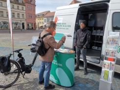 ein Besucher steht mit seinem Fahrrad vor dem Infomobil und unterh&auml;lt sich mit unserem Mobilreferenten.