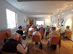 Die Teilnehmenden sitzen im Raum und schauen zur Pr&auml;sentation an der Wand