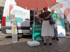 Eines Besucherin steht vor dem Infomobil und unterh&auml;lt sich mit unserem Referenten und Kooperationspartner vor Ort