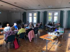 Der B&uuml;rgersaal in Schwarzheide ist gef&uuml;llt mit vielen sitzenden Senior:innen, die einem Vortrag zuh&ouml;ren.