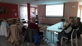 Die Teilnehmenden sitzen im Raum und schauen zur Pr&auml;sentation an der Wand