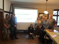 Die Teilnehmenden der Veranstaltung in Farsleben stehen mit der Referentin vor der Leinwand, auf die die Pr&auml;sentation gezeigt wird.