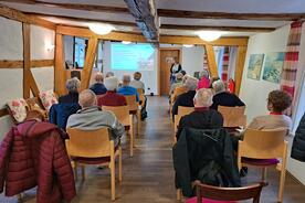 Die Teilnehmenden aus Bad Hersfeld sitzen und folgen der Pr&auml;sentation von Theresa.