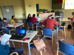 Die Teilnehmenden sitzen an Tischen und f&uuml;llen die Evaluation aus. Ein Teilnehmer hat auf seinem Tisch einen Laptop. 