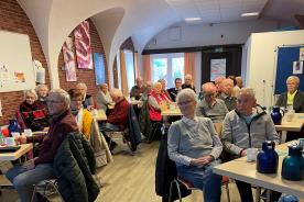 Die Teilnehmenden sitzen im Raum und schauen zur Pr&auml;sentation an der Wand