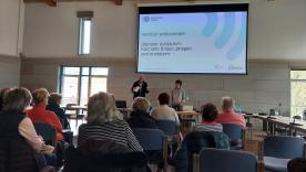 Die Teilnehmenden sitzen im Raum und schauen zur Pr&auml;sentation an der Wand