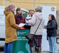 Um den Info-Stand des Digitalen Engel stehen f&uuml;nf Menschen und unterhalten sich. Im Hintergrund steht das Info-Mobil sowie ein Rollup der Hillerschen Villa.