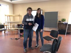 Die Referentin vom Digitalen Engel und Teilnehmerin Karola stehen nebeneinander und l&auml;cheln in die Kamera. Karola h&auml;lt ihr Smartphone und den Wegweiser mit den Angeboten in der Hand.
