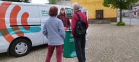 Das Info-Mobil steht auf dem Marktplatz in Mirow. Vor dem Mobil unterh&auml;lt sich die Referentin vom Digitalen Engel mit einem Ehepaar.