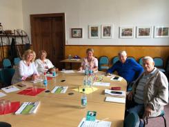 Die Ansprechpartnerin der Stadtbibliothek sitzt mit vier Senior:innen an einem runden Tisch. Auf dem Tisch liegen Smartphones und Brosch&uuml;ren.