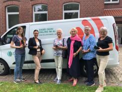 Petra steht mit f&uuml;nf Seniorinnen vor dem Info-Mobil. Alle halten ein Smartphone in der Hand und gucken in die Kamera.