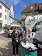 Die Besucherin und Theresa stehen auf dem Marktplatz und l&auml;cheln in die Kamera.