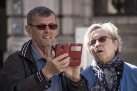 Ein &auml;lterer Mann und eine Frau blicken auf ein rotes Smartphone