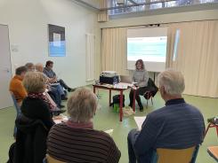 Die Teilnehmenden aus Magdeburg sitzen auf St&uuml;hlen und h&ouml;ren bei Theresas Vortrag zu.