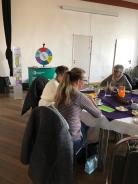 Drei Frauen sitzen am gedeckten Fr&uuml;hst&uuml;ckstisch, im Hintergrund ist der Stand vom Digitalen Engel.