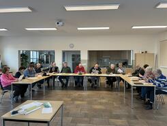Die 16 Teilnehmenden sitzen an Tischen in U-Form im gro&szlig;en Gemeinderaum und f&uuml;llen Feedbackb&ouml;gen aus.