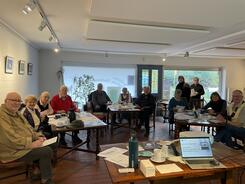 Die Teilnehmenden im K&uuml;nstlerhaus in Worpswede sitzen im Halbkreis an gedeckten Tischen und l&auml;cheln in die Kamera.