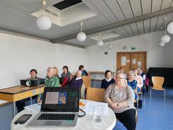 Die Teilnehmenden sitzen im Raum und schauen zur Pr&auml;sentation an der Leinwand