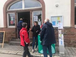 Theresa informiert eine Besucherin und einen Besucher am Infostand vor dem Begegnungszentrum &uuml;ber sichere Passw&ouml;rter.