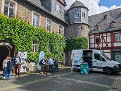 Mehrere Personen stehen an Infost&auml;nden im Hof vor dem Museumsgeb&auml;ude 