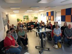 Ein Foto vom Veranstaltungsraum im Senioren- und Pflegest&uuml;tzpunkt Burgdorf. In der Mitte steht ein Beamer. Darum herum sitzen knapp 35 Senior:innen auf St&uuml;hlen, die nach vorne blicken.