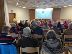 DIe &uuml;ber 30 Teilnehmenden sitzen und schauen auf die Endfolie der Pr&auml;sentation, die auf einer Leinwand gezeigt wird.