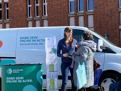 Petra ist an dem Info-Stand vor dem Info-Mobil mit einer &auml;lteren Dame im Gespr&auml;ch.