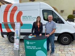 Petra (links) steht zusammen mit dem Seniorenbeauftragten Herr Wild am Info-Stand vor dem Info-Mobil, das auf dem Marktplatz vor dem Hirschauer Rathaus platziert ist.