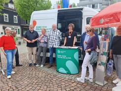 Mehrere Personen stehen um das Infomobil herum und blicken in die Kamera.