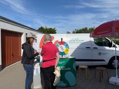 Petra (links) steht mit einer Seniorin (rechts) am Info-Stand des Info-Mobils und ist mit ihr in einem Gespr&auml;ch vertieft.