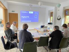 Die Teilnehmenden sind von hinten und von der Seite zu sehen und schauen auf die Leinwand mit der Titelfolie zur digitalen Zeitung der Volksstimme.