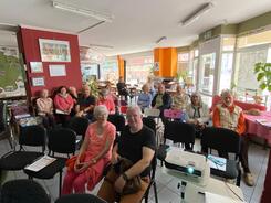 In der kleinen Markthalle in Stendal sitzen Senior:innen verteilt auf St&uuml;hlen im Raum und blicken nach vorne in die Kamera.