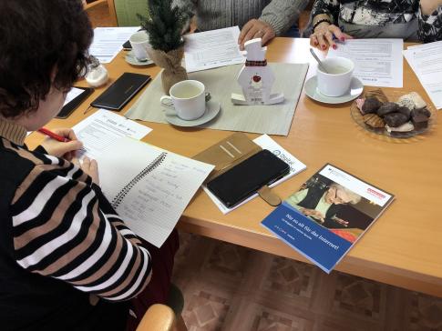 Frau am Tisch mit Smartphone und Brosch&uuml;re "Nie zu alt f&uuml;rs Internet"