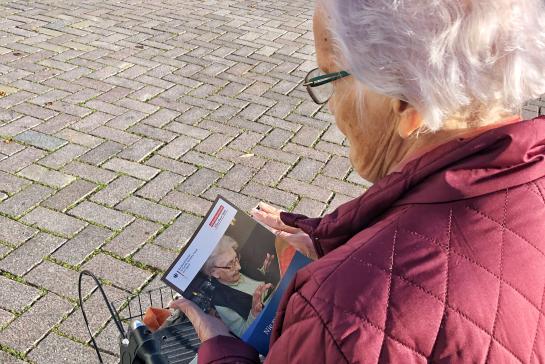 Seniorin steht auf dem Marktplatz in Ratzeburg und bl&auml;ttert im Buch