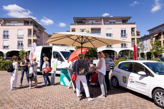 Referentin Petra Rollfing im Gespr&auml;ch mit drei Damen. Daneben unterh&auml;lt sich Kerstin Wasmuth mit einer Frau. Im Hintergrund steht das Engel-Mobil sowie das Auto der Arbeiterwohlfahrt. 