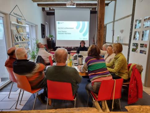 Die Teilnehmenden sitzen im Raum und blicken zur Pr&auml;sentation an der Wand