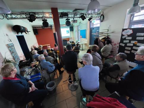 Die Teilnehmenden sitzen im Raum und blicken zur Pr&auml;sentation 