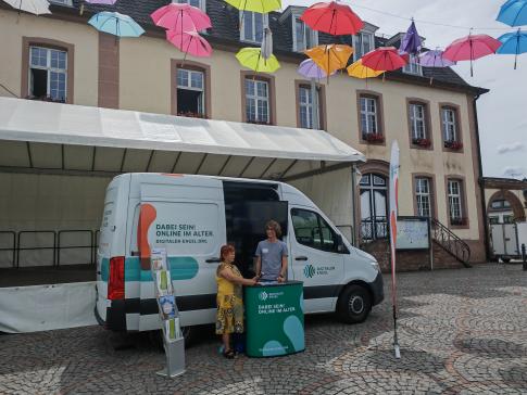 Eine Besucherin steht vor dem Infomobil und unterh&auml;lt sich mit unserem Referenten