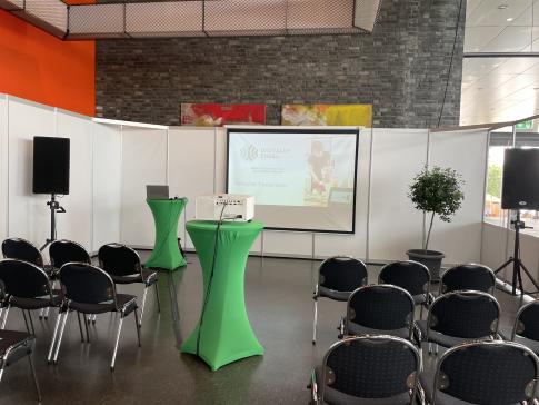 Die Titelfolie der Pr&auml;sentation sowie einige St&uuml;hle und zwei Stehtische sind in der Oberrheinhalle in Offenburg zu sehen.