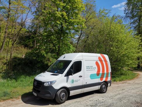 Infomobil steht vor B&auml;umen auf einem Parkplatz