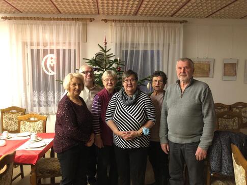 Vier Teilnehmerinnen und zwei Teilnehmer stehen vor einem Tannenbaum im Ortwiger Gemeindezentrum und l&auml;cheln in die Kamera.
