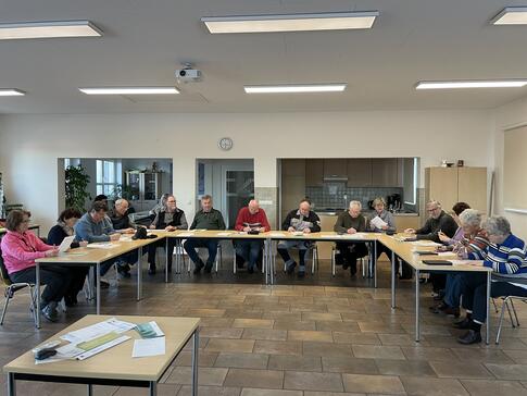 Die 16 Teilnehmenden sitzen an Tischen in U-Form im gro&szlig;en Gemeinderaum und f&uuml;llen Feedbackb&ouml;gen aus.