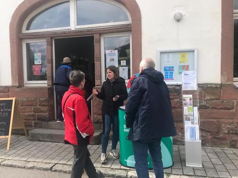 Theresa informiert eine Besucherin und einen Besucher am Infostand vor dem Begegnungszentrum &uuml;ber sichere Passw&ouml;rter.